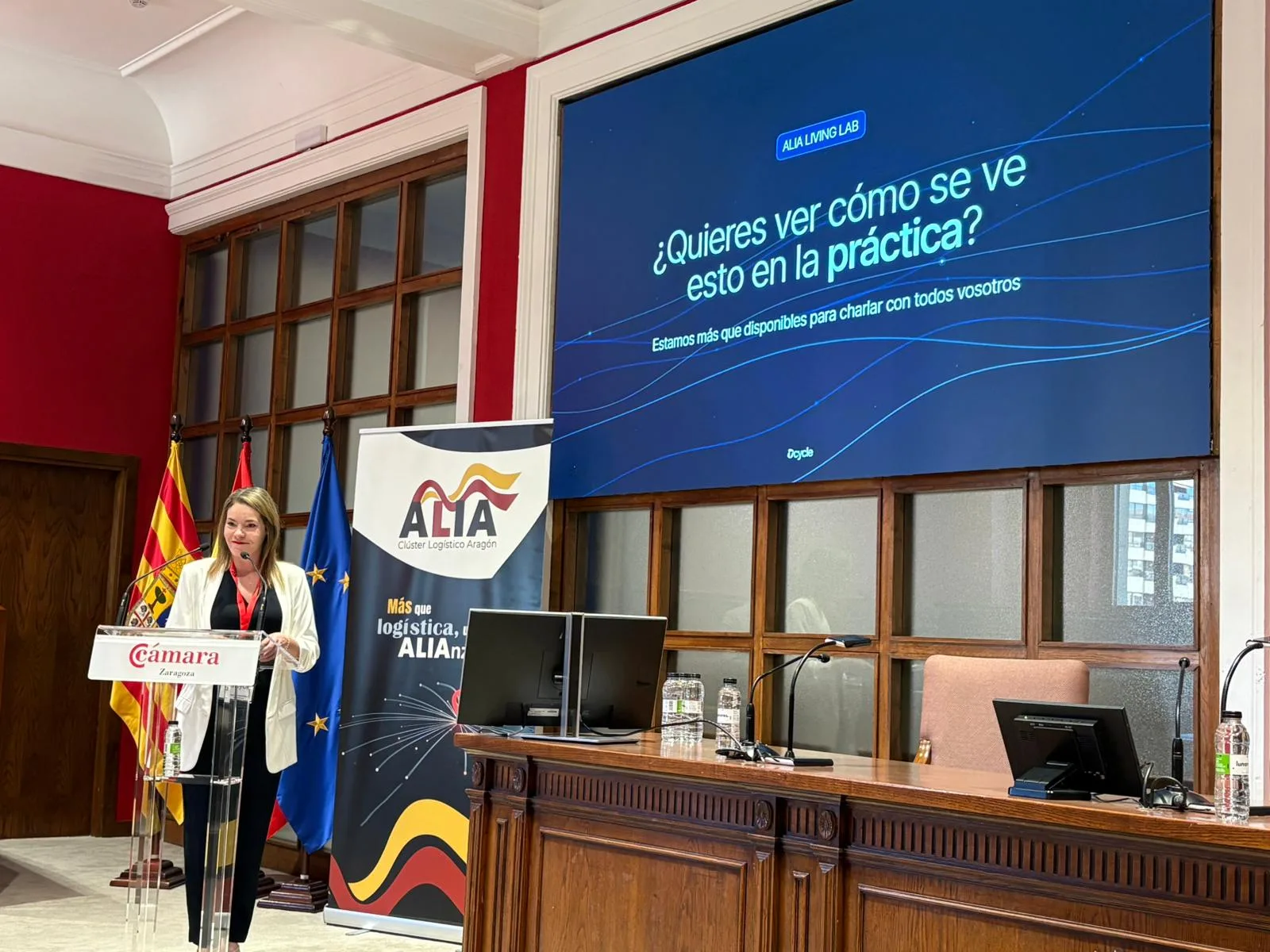 Carla de Reparaz at the podium with the closing slide inviting attendees to see Dcycle in practice